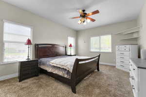 Bedroom featuring ceiling fan, light colored carpet, and baseboards