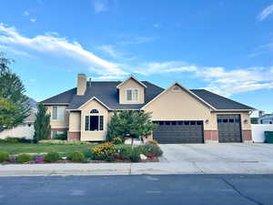 View of front of property with driveway, a chimney, a front yard, brick siding, and an attached garage