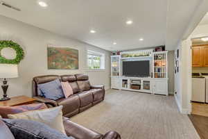 Living area with washing machine and dryer, recessed lighting, visible vents, and wood finished floors