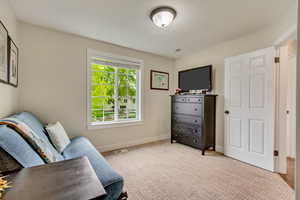 Sitting room with visible vents, light carpet, and baseboards
