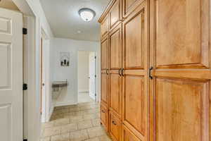Corridor featuring baseboards, light tile patterned floors, and a textured ceiling