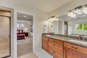 Ensuite bathroom with a sink, a shower stall, connected bathroom, and baseboards
