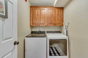 Clothes washing area featuring a textured ceiling, separate washer and dryer, and cabinet space
