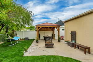 View of patio with an outdoor fire pit, a gazebo, and a fenced backyard
