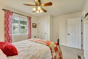 Bedroom featuring visible vents, ceiling fan, light colored carpet, and baseboards