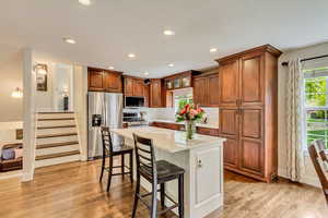 Kitchen featuring recessed lighting, a breakfast bar area, stainless steel appliances, light countertops, and light wood finished floors