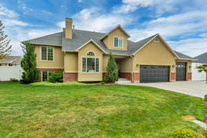 View of front of home with concrete driveway, a front yard, stucco siding, brick siding, and a garage