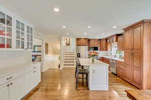 Kitchen with glass insert cabinets, a sink, a breakfast bar, stainless steel appliances, and a kitchen island