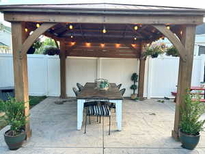 View of patio with a gazebo, outdoor dining area, and fence