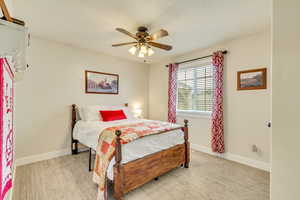 Bedroom featuring light colored carpet, ceiling fan, and baseboards