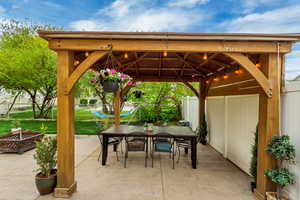 View of patio / terrace featuring fence, a gazebo, outdoor dining space, and a fire pit