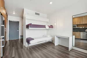 Bedroom with wood finished floors, recessed lighting, visible vents, and a sink