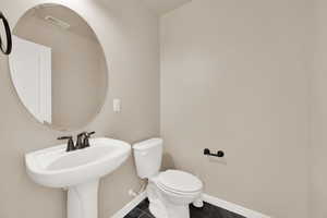 Half bathroom with visible vents, toilet, tile patterned flooring, and baseboards