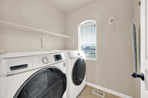 Clothes washing area featuring light tile patterned floors, visible vents, baseboards, separate washer and dryer, and laundry area