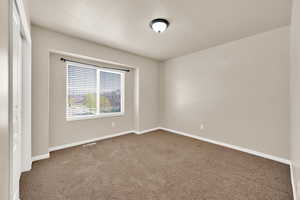 Empty room with baseboards, visible vents, and carpet flooring