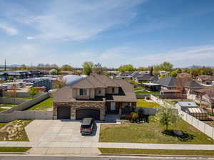 View of front facade with concrete driveway, fence private yard, stone siding, and an attached garage