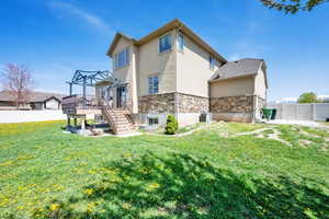 Back of house with a deck, a fenced backyard, stucco siding, stone siding, and stairs