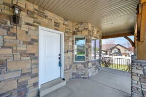Doorway to property featuring a porch and stone siding