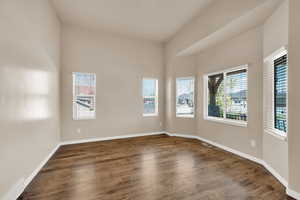 Empty room with baseboards, visible vents, and wood finished floors