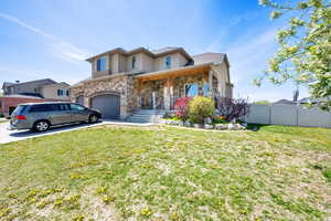 View of front of house featuring fence, a front yard, concrete driveway, and stone siding