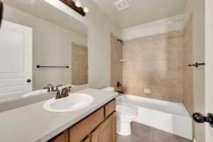 Bathroom with vanity, bathing tub / shower combination, toilet, visible vents, and tile patterned flooring