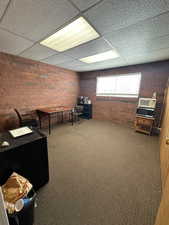 Interior space featuring a paneled ceiling and brick wall