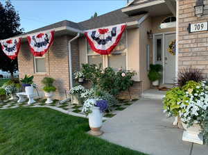 Doorway to property featuring stucco siding, brick siding, a yard, and a shingled roof