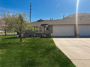 View of front of property with a garage, brick siding, a front yard, and concrete driveway
