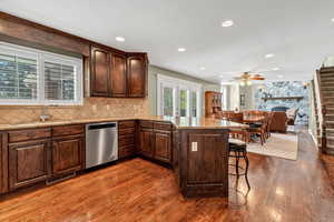 Kitchen featuring stainless steel dishwasher, a kitchen breakfast bar, a sink, and dark wood-type flooring