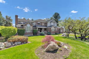 View of front of property with a front lawn, brick siding, and a chimney