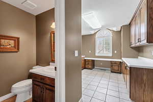 Bathroom featuring tile patterned floors, vanity, baseboards, toilet, and visible vents