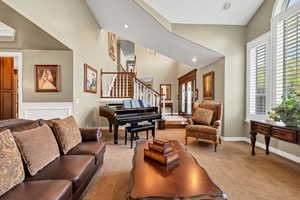 Living room featuring carpet flooring, baseboards, recessed lighting, stairs, and high vaulted ceiling