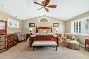Bedroom with carpet floors, visible vents, lofted ceiling, and a ceiling fan