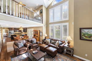 Living room with high vaulted ceiling, a ceiling fan, baseboards, dark wood-type flooring, and visible vents