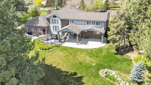 Rear view of property featuring a chimney, a tile roof, a yard, and a patio