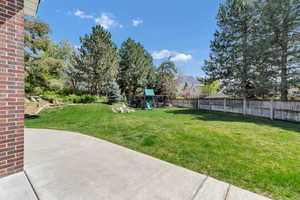 View of yard with a patio area, a playground, and fence
