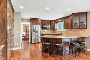 Kitchen with a sink, wood finished floors, a breakfast bar area, stainless steel appliances, and a peninsula