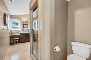 Full bathroom with a shower stall, vaulted ceiling, visible vents, toilet, and vanity