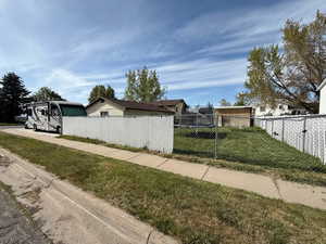 View of side of home with fence and a yard
