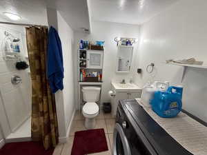 Bathroom with a textured ceiling, toilet, washer / clothes dryer, and baseboards