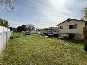 View of yard featuring a trampoline, a jacuzzi, and a fenced backyard