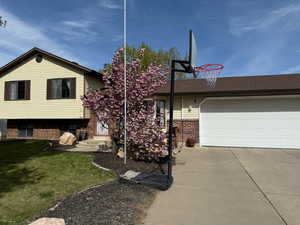 View of front of house featuring brick siding, driveway, an attached garage, and a front yard
