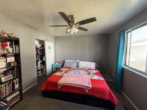 Bedroom with ceiling fan, a textured ceiling, carpet, and a closet