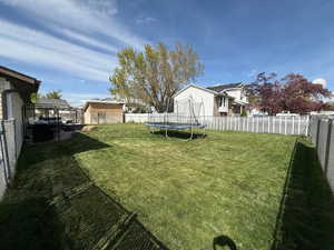 View of yard featuring a trampoline and a fenced backyard