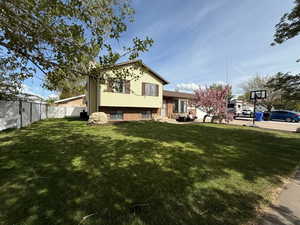 Back of property featuring a lawn, brick siding, and fence