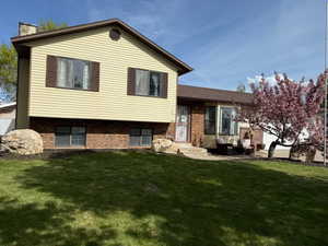 Rear view of property featuring a lawn, an outdoor living space, brick siding, and a chimney