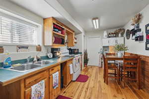Kitchen featuring open shelves, electric stove, light wood-type flooring, and a sink