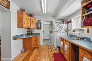 Kitchen with brown cabinets, light wood-style flooring, a sink, freestanding refrigerator, and baseboards