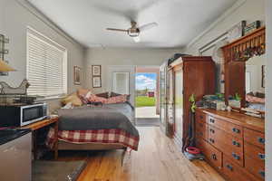 Bedroom with hardwood / wood-style floors, access to exterior, a ceiling fan, and ornamental molding