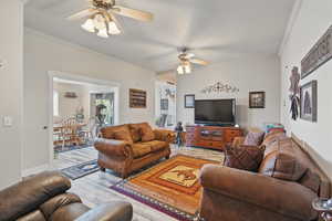 Living area featuring light wood-style floors, a ceiling fan, and ornamental molding